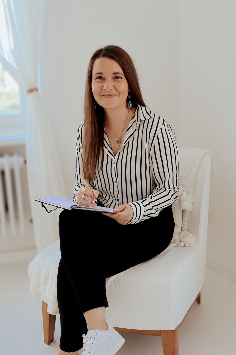 Julia Rau mit Notizbuch auf einem hellen Sessel